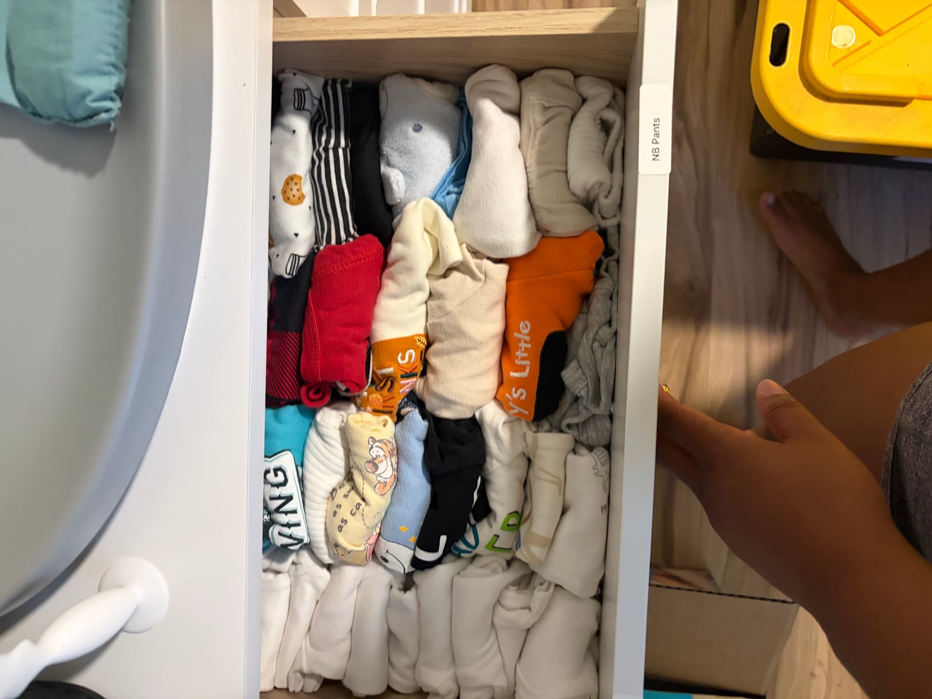 Newborn clothing folded upright in a labeled drawer