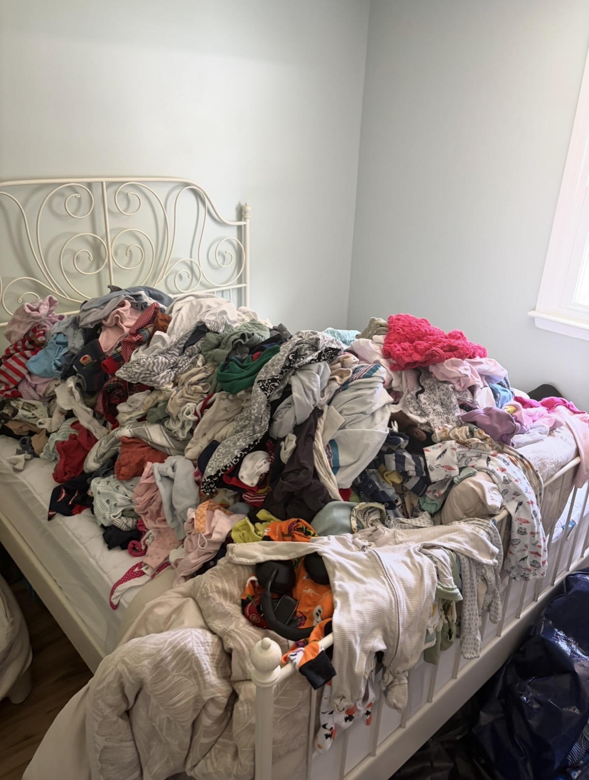 Outgrown children’s clothing gathered on a bed before a home reset